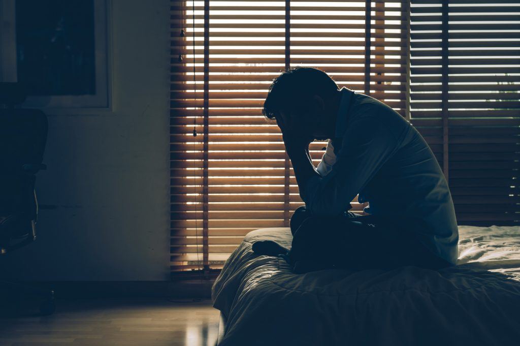Sad businessman sitting head in hands on the bed in the dark bedroom with low light environment, dramatic concept, vintage tone color What Happens When My Domestic Violence Protective Order Expires?