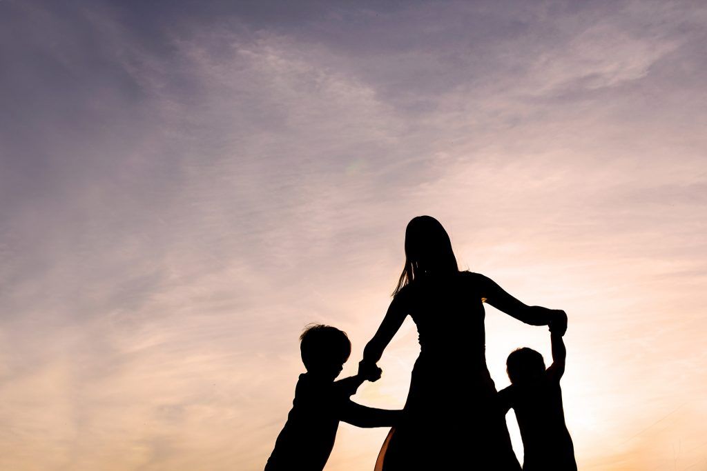 Silhouette of Mother and Children Dancing at Sunset Modification of North Carolina Child Custody Order Due to Mother’s Improvement